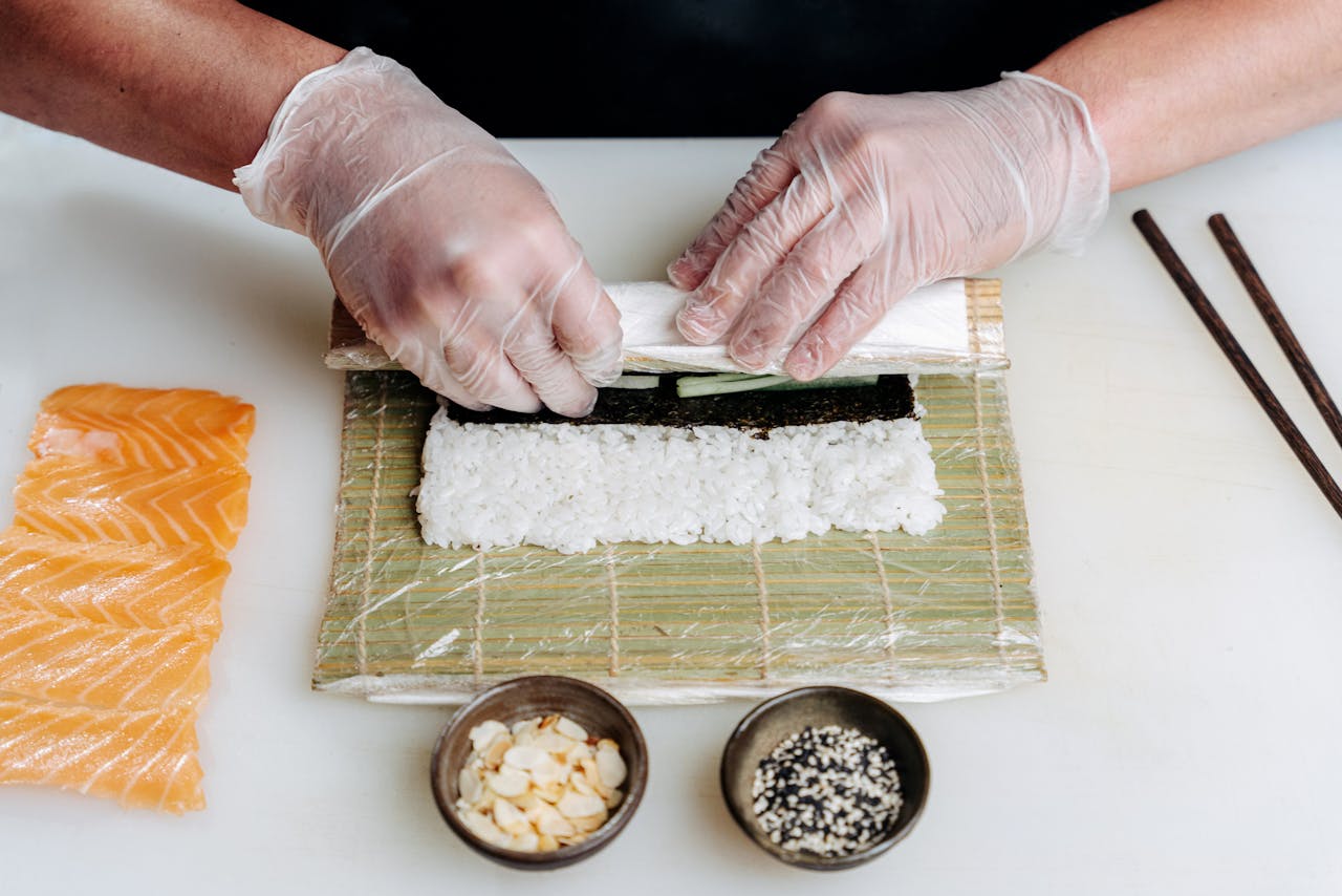 Close-up of sushi being prepared with fresh salmon and ingredients on a bamboo mat.